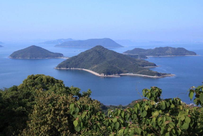 写真中央で3つの山が連なって見える島が粟島