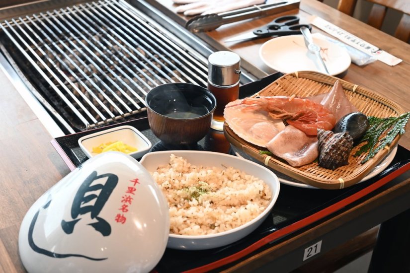 食事処では新鮮な魚介を自分で焼いて食べる浜焼きが人気。写真は「浜焼き５点盛り」（1,800円）、千里浜名物の「貝めし」（660円）